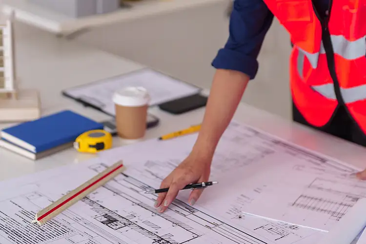 Architekt überprüft komplexe Baupläne für Bauprojekte und Stadtentwicklungsvorhaben und entwirft mit Präzision innovative Zukunftsstrukturen am Schreibtisch.